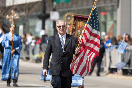 Chicago, Illinois, USA - April 29, 2018  Greek man  carrying the USA flag during the Greek Independence  Day Paradeのeditorial素材