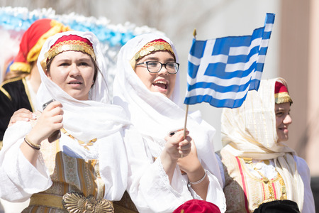 Chicago, Illinois, USA - April 29, 2018 Women wearing traditional clothing waving the greek flag...