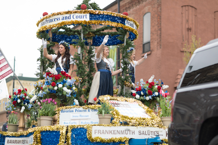 Holland, Michigan, USA - May 12, 2018 Beuty Queens on top of a float surrounded by tulip flowers and wearing traditional dutch clothing go down the road at the Muziek Parade, during the Tulip Time Festivalのeditorial素材