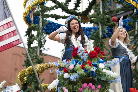 Holland, Michigan, USA - May 12, 2018 Beuty Queens on top of a float surrounded by tulip flowers and wearing traditional dutch clothing go down the road at the Muziek Parade, during the Tulip Time Festivalのeditorial素材