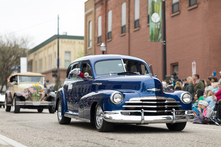 Holland, Michigan, USA - May 12, 2018 An old classic Chevrolet, followed by other classic cars, goes down the road at the Muziek Parade, during the Tulip Time Festivalのeditorial素材