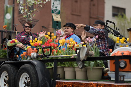 Holland, Michigan, USA - May 12, 2018 Woman and children wearing traditional dutch clothing surrounded by tulip flowers, riding a trailer at the Muziek Parade, during the Tulip Time Festivalのeditorial素材