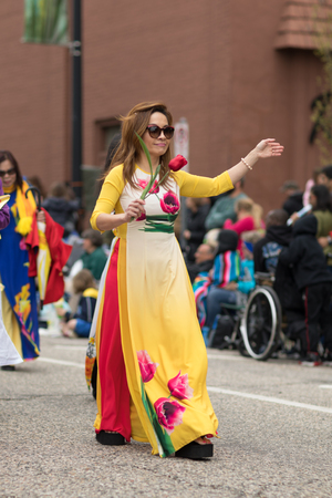 Holland, Michigan, USA - May 12, 2018 Members of Michigan Vietnamese American Community wearing traditional clothing and waving american and vietnamese flags at the Muziek Parade, during the Tulip Time Festivalのeditorial素材