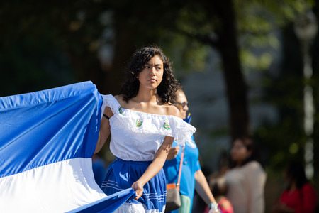 Washington, D.C., USA - September 29, 2018: The Fiesta DC Parade, Woman from el salvador wearing traditional clothing holding a large Salvadoran Flagのeditorial素材