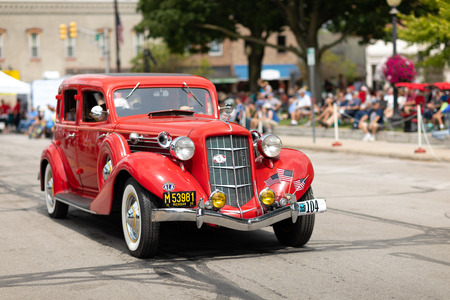 Auburn, Indiana, USA - September 9, 2018 The Auburn Cord Duesenberg Festival, An Auburn classic car with american flags on the front bumper driving down the street during the paradeのeditorial素材
