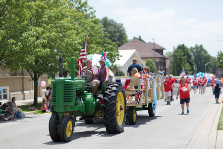 Kokomo, Indiana, USA - June 30, 2018: Haynes Apperson Parade, Old John Deere classic tractor color green , pulling a wagon down the road and carrying the american flagのeditorial素材