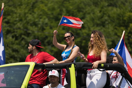 Chicago, Illinois, USA - June 16, 2018: The Puerto Rican Day Parade, Woman waving the puerto rican flag going down the street during the paradeのeditorial素材