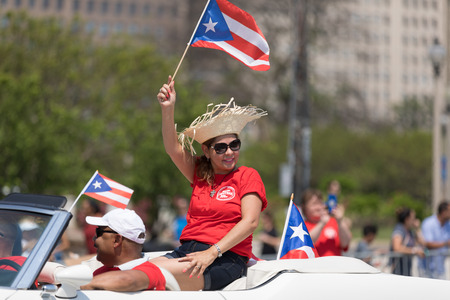 Chicago, Illinois, USA - June 16, 2018: The Puerto Rican Day Parade, Woman waving the puerto rican flag going down the street during the paradeのeditorial素材