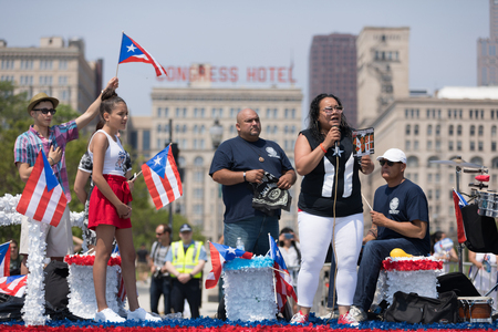 Chicago, Illinois, USA - June 16, 2018: The Puerto Rican Day Parade, Woman sings the Puerto Rican National Anthem at the start of the parade while holding a sign that Reminds of the Hurriacan losses in Puerto Ricoのeditorial素材