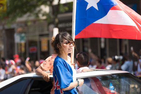 Chicago, Illinois, USA - June 16, 2018: The Puerto Rican People's Parade, Puerto rican woman waving the puerto rican flag going down the road during the paradeのeditorial素材