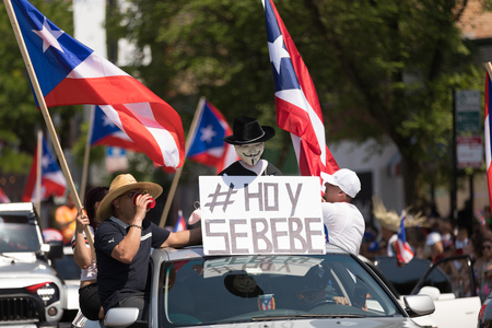 Chicago, Illinois, USA - June 16, 2018: The Puerto Rican People's Parade, Puerton rican people riding on cars celebrating with puerto rican flags and a sign that says Hoy Se Bebeのeditorial素材