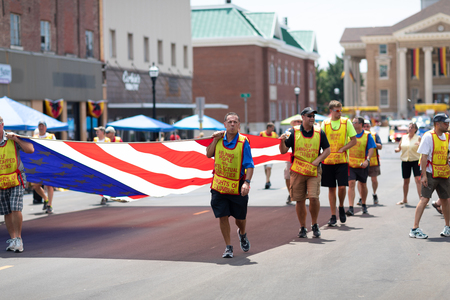 Jasper, Indiana, USA - August 5, 2018: The Strassenfest Parade, Men from the Knights of Columbus, promoting help for people with Disabilities, carrying a giant american flagのeditorial素材