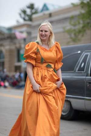 Stoughton, Wisconsin, USA - May 20, 2018: Annual Norwegian Parade, Woman wearing an orange dress and a crown, waving at the spectatorsのeditorial素材