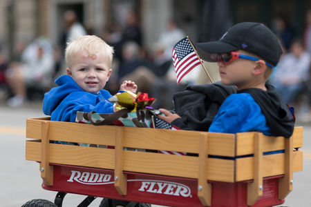 Stoughton, Wisconsin, USA - May 20, 2018: Annual Norwegian Parade, Children riding on a Radio Flyer, wagon, with american flags, during the paradeのeditorial素材