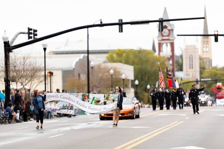Wilmington, North Carolina, USA - April 6, 2019: The North CarolinaAzalea Festival, Women carry the Azalea Festival Parade banner down the streetのeditorial素材