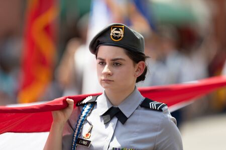 Buckhannon, West Virginia, USA - May 18, 2019: Strawberry Festival, Youg woman, member of the JROTC, wearing military Uniform, carrying a large American flag down Main Streetのeditorial素材
