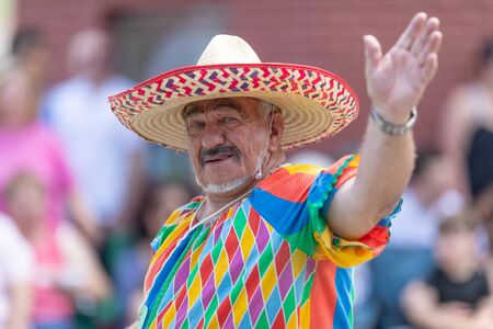 Buckhannon, West Virginia, USA - May 18, 2019: Strawberry Festival, Man wearing a clown outfit, with a mexican sombrero, smiling waving at the cameraのeditorial素材
