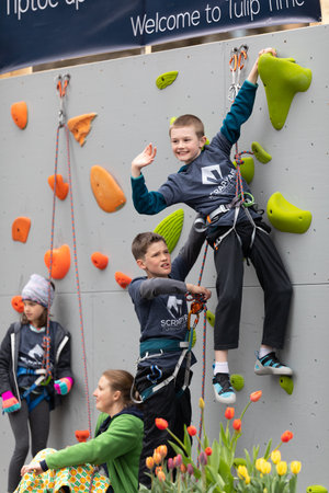 Holland, Michigan, USA - May 11, 2019: Tulip Time Parade, Two boys climbing a wall, on a trailer, going down the road during the paradeのeditorial素材