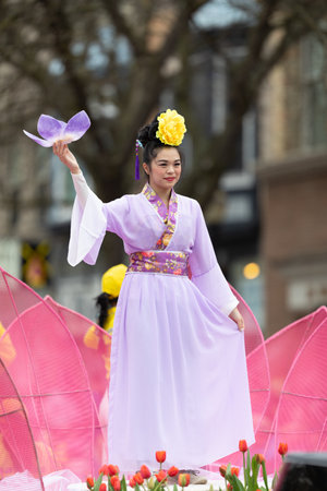 Holland, Michigan, USA - May 11, 2019: Tulip Time Parade, Asian woman wearing a kimono and holding a tulip flower, smiling and waving at the spectatorsのeditorial素材