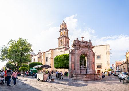 Santiago de Queretaro, Queretaro, Mexico - November 24, 2019: View down Francisco I Madero, with people walking by the neptune fountain, Temple of Life Sanctuary, and the Parish of the Sacred Heart of Jesus Of St. Claireのeditorial素材