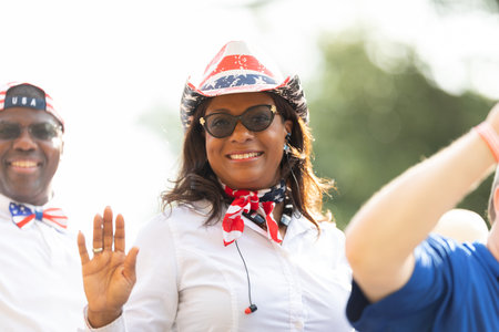 Arlington, Texas, USA - July 4, 2019: Arlington 4th of July Parade, Woman wearing a cowboy hat with the colors of the American flag, smiles and waves to the cameraのeditorial素材