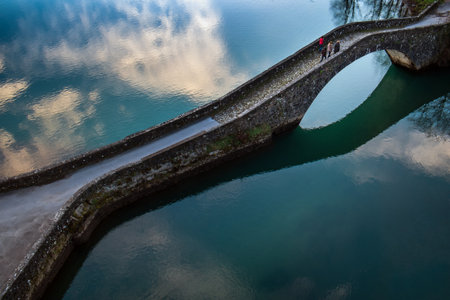 Artificial lake of Pontecosi in Garfagnana in the region of Tuscany, railroad bridge and a little church from a stone little bridgeの写真素材