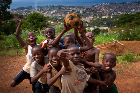 Freetown, Sierra Leone - June 8, 2013: Children greet playing football, in the background the soccer field during a match of the Cup of Africaのeditorial素材