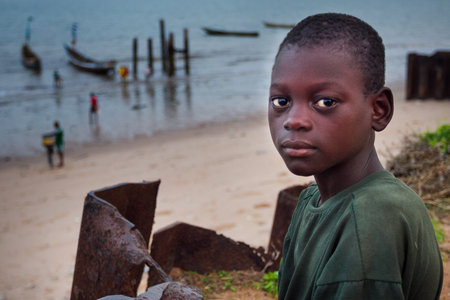 Yongoro, Sierra Leone - May 30, 2013: West Africa, the beaches of Yongoro in front of Freetown, portrait of child with boats in the backgroundのeditorial素材