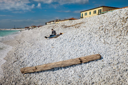 MARINA DI PISA, ITALY - Avril 24, 2017: View of the sea and the beach of white pebbles, people take the first sun of the season in Marina di Pisa Tuscanyのeditorial素材