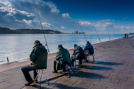 LISBON, PORTUGAL - January 28, 2011: four unknown fishermen beside the Tagus River, Belem Running Route, Lisbon, Portugalのeditorial素材
