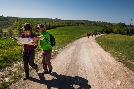 ASCIANO, TUSCANY, Italy - April 25, 2018: trekking, Asciano with ravines, farms in a harsh landscape, arrived in Serre di Rapolano known for the travertine quarries, but from the medieval heart. Unknown people walking along the famous white roadsのeditorial素材