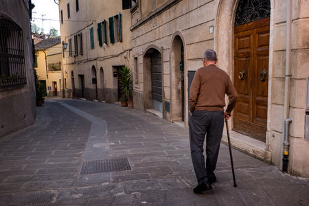 ASCIANO, TUSCANY, Italy - April 25, 2018: trekking, Asciano with ravines, farms in a harsh landscape, arrived in Serre di Rapolano known for the travertine quarries, but from the medieval heart. Unknown man walks in the city streetsのeditorial素材