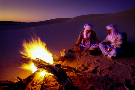 TASSILI NâAJJER, ALGERIA - JANUARY 10, 2002: unknown men at sunset with fire in the sand dunes of the Algerian Sahara desert, Africa, Tassili N'Ajjer National Parkのeditorial素材