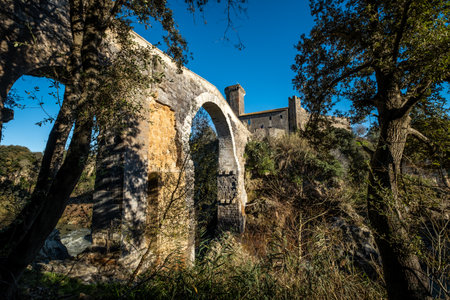 VULCI, ITALY - DECEMBER 26, 2019: The Badia bridge and castle, medieval dating back to the 13th...