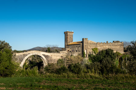 VULCI, ITALY - DECEMBER 26, 2019: panoramic view from the countryside of the Badia bridge and castle, medieval dating back to the 13th century, an ancient Etruscan city in the territory of Canino and Montalto di Castro, in the province of Viterbo, in the のeditorial素材