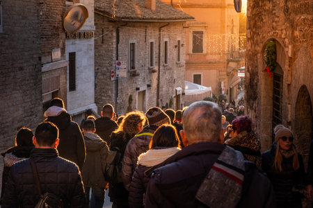 Last lights of sunset with tourists in the Repubblica street in Gubbio, medieval town in Umbria in the province of Perugia, central Italyのeditorial素材