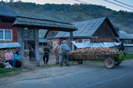 MARAMURES, ROMANIA - OCTOBER 10, 2014: the isolated Carpathian region of Romani, unknown people sitting near the typical wooden houses. Romania, Europeのeditorial素材