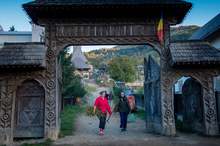 MARAMURES, ROMANIA - OCTOBER 10, 2014: unknown woman walking near the typical wooden houses. Romania, Europeのeditorial素材
