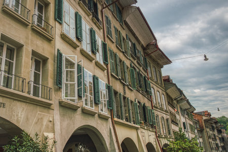 Houses in a row above a portico exterior in a Swiss historical district. Lots of colourful, old style   louvered shutters (jalousie) outline an old fashion building facade - Bern, Switzerlandのeditorial素材