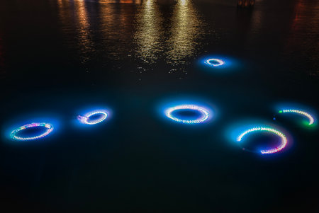 Underwater neon or led multi coloured lights rings (circles) shine on the dark sea bottom or seafloor representing organisms glowing in darkness. Bright circular lights on sea floor convey disquietudeの写真素材
