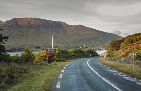 People walk on the scenic Connemara loop by Killary Harbour or Fjord at sunset. Touristic, scenic Connemara road on the west coast of Ireland by the Atlantic Ocean among the mountains. County Galwayの写真素材
