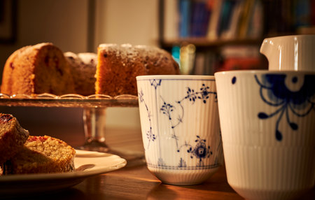 Luxury, old fashioned mug of warm coffee with a slice gf donut in a romantic environment. Cozy ambient with sliced doughnut and a luxurious cup of hot steamy tea conveys cozinessの写真素材
