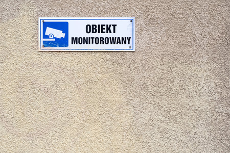 under video surveillance text in Polish, blue CCTV symbol on the wall in Warsaw, Polandの写真素材