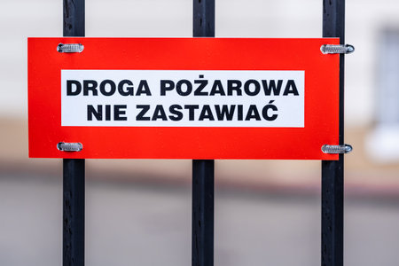 fire road, keep clear text in Polish on the sign mounted to the metal fence, white and red plate, black lettersの写真素材