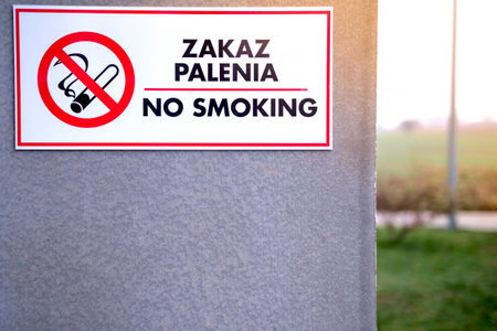 bilingual no smoking text and sign in Polish and English on the wall, blurred background, warm sun right topの写真素材