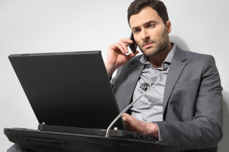 Young businessman using cell phone, over grey backgroundの写真素材