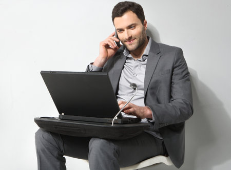 Young businessman using cell phone, over grey backgroundの写真素材
