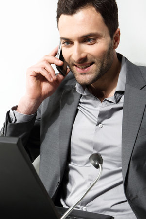 Young businessman using cell phone, over grey backgroundの写真素材
