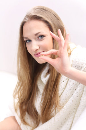 Young long-haired blonde sitting on a sofa  She holds a pill の写真素材