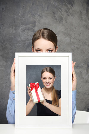 Girl holds a picture of a girl and a giftの写真素材